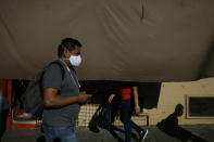 A man with a mask walks on a sidewalk past street vendors during the coronavirus pandemic in the Westlake neighborhood of Los Angeles, Thursday, May 21, 2020. While most of California is welcoming a slight return toward normal this holiday weekend, Los Angeles will not be joining the party. (AP Photo/Jae C. Hong)