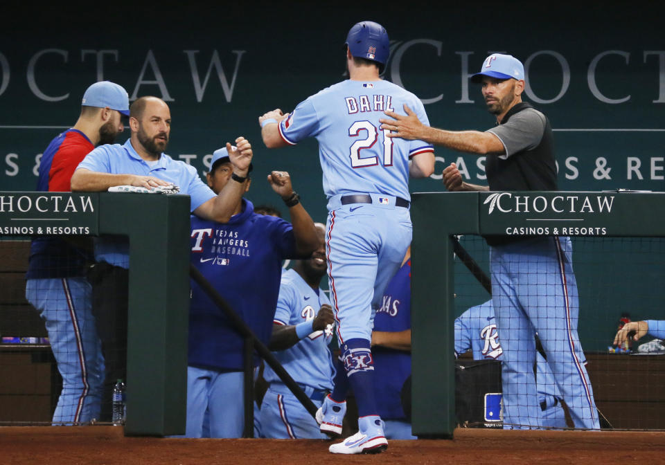 Texas Rangers' David Dahl, center, is greeted at the dugout steps by manger Chris Woodward, right, after scoring against the Oakland Athletics during the fifth inning of a baseball game in Arlington, Texas, Sunday, July 11, 2021. (AP Photo/Ray Carlin)