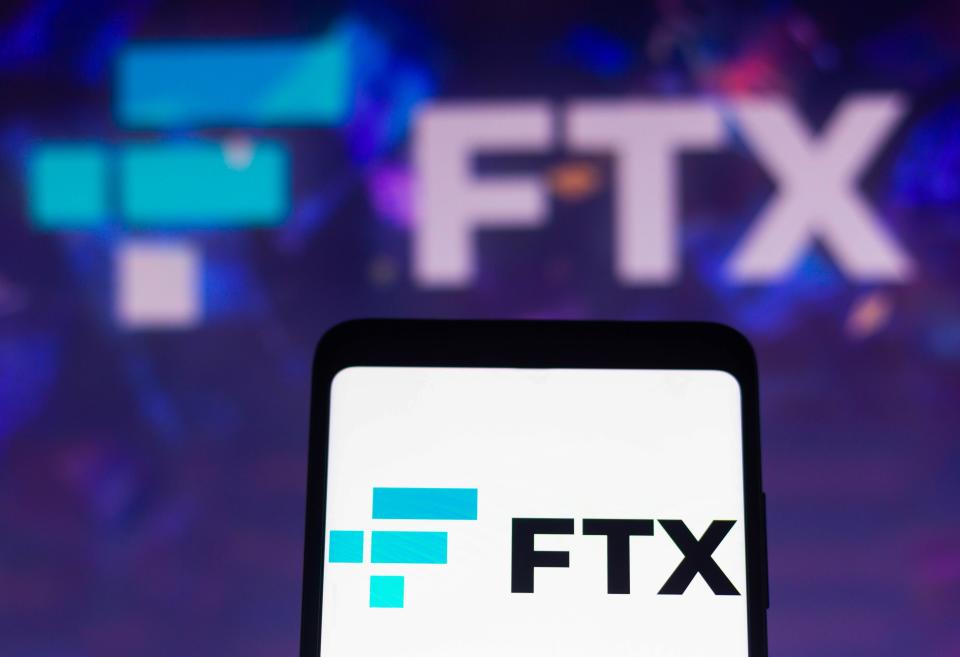 In this photo illustration, the FTX Crypto Derivatives Exchange logo is displayed on a smartphone screen and in the background.