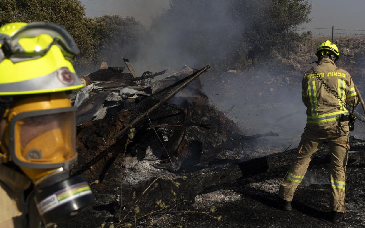 Firefighters extinguish a fire at a kibbutz in Naftali caused by a drone attack from Lebanon, on Tuesday