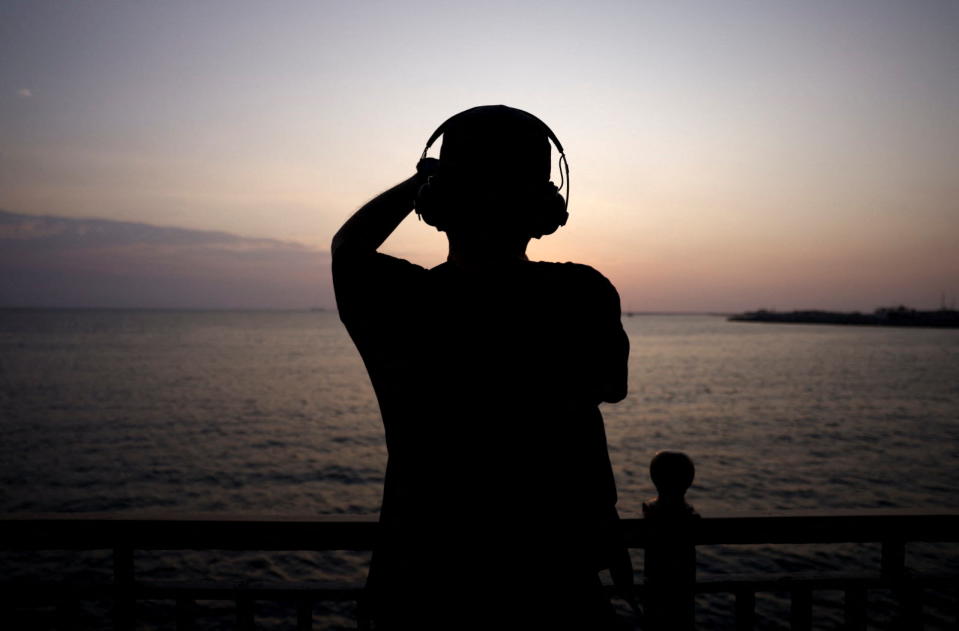Un hombre disfruta de un audiolibro mientras contempla el ocaso - REUTERS/Dinuka Liyanawatte