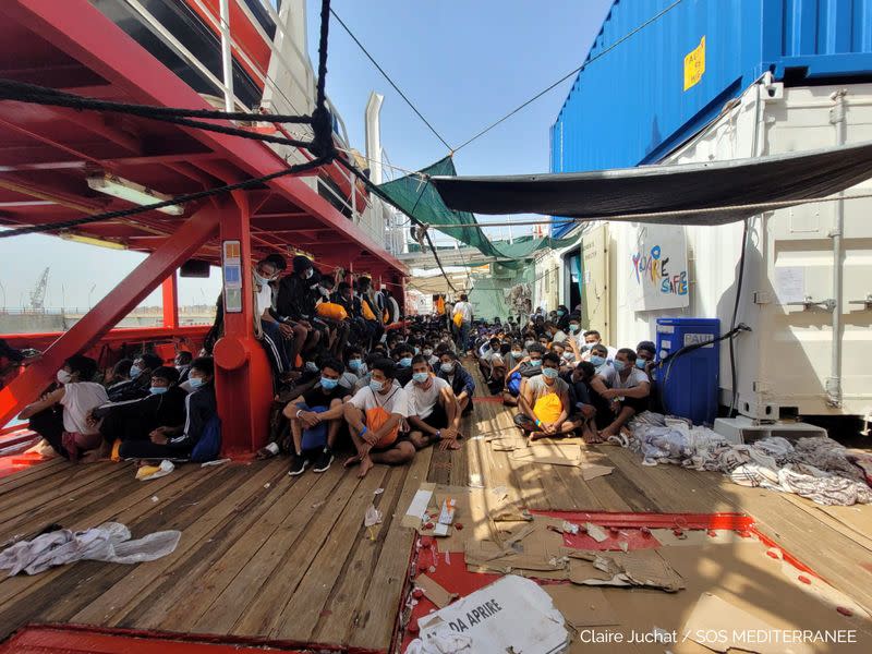 Migrants sit onboard "Ocean Viking" ship as they wait to disembark, in Augusta