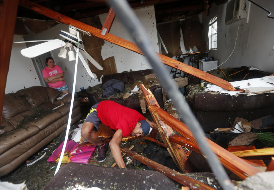 Dorian Carter looks under furniture for a missing cat after several trees fell on their home in Panama City.