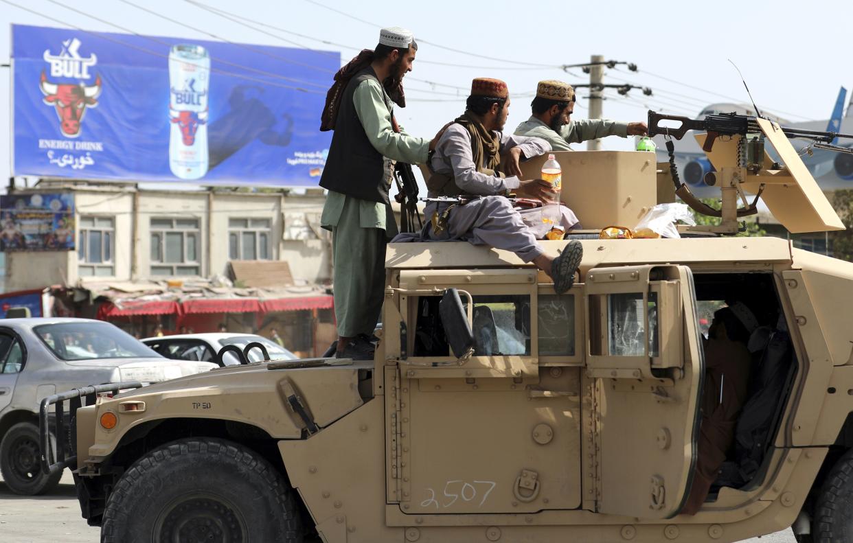 Taliban fighters stand guard in front of the Hamid Karzai International Airport in Kabul, Afghanistan on Monday, Aug. 16, 2021. Thousands of people packed into the Afghan capital's airport on Monday, rushing the tarmac and pushing onto planes in desperate attempts to flee the country after the Taliban overthrew the Western-backed government.