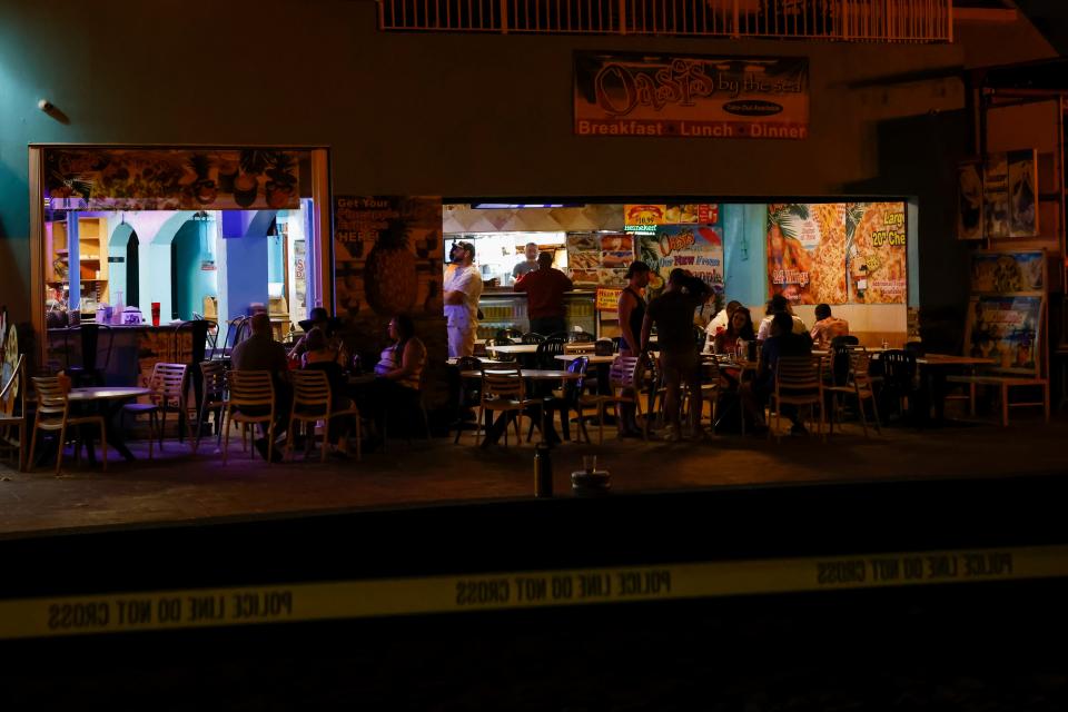 People are seen at a bar next to a crime scene as law enforcement officers respond to a shooting at Hollywood Beach on 29 May 2023 in Hollywood, Florida (Getty Images)