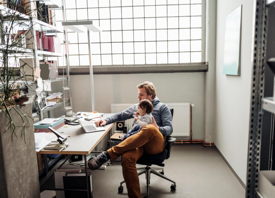 Father working while holding infant daughter.