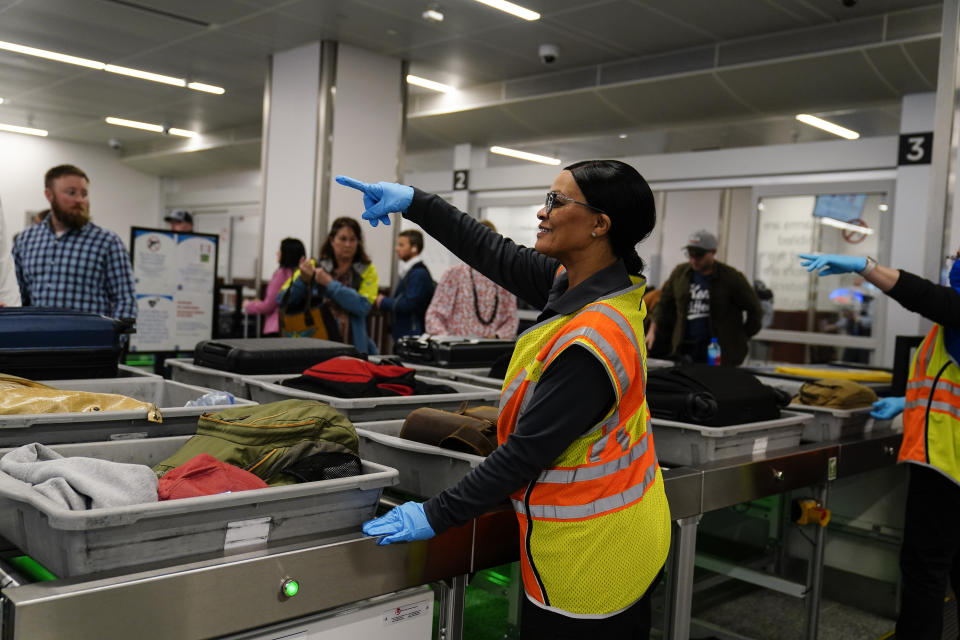 A worker points as people wait for the belongings at the Transportation Security Administration security area at the Hartsfield-Jackson Atlanta International Airport on Wednesday, Jan. 25, 2023, in Atlanta. (AP Photo/Brynn Anderson)
