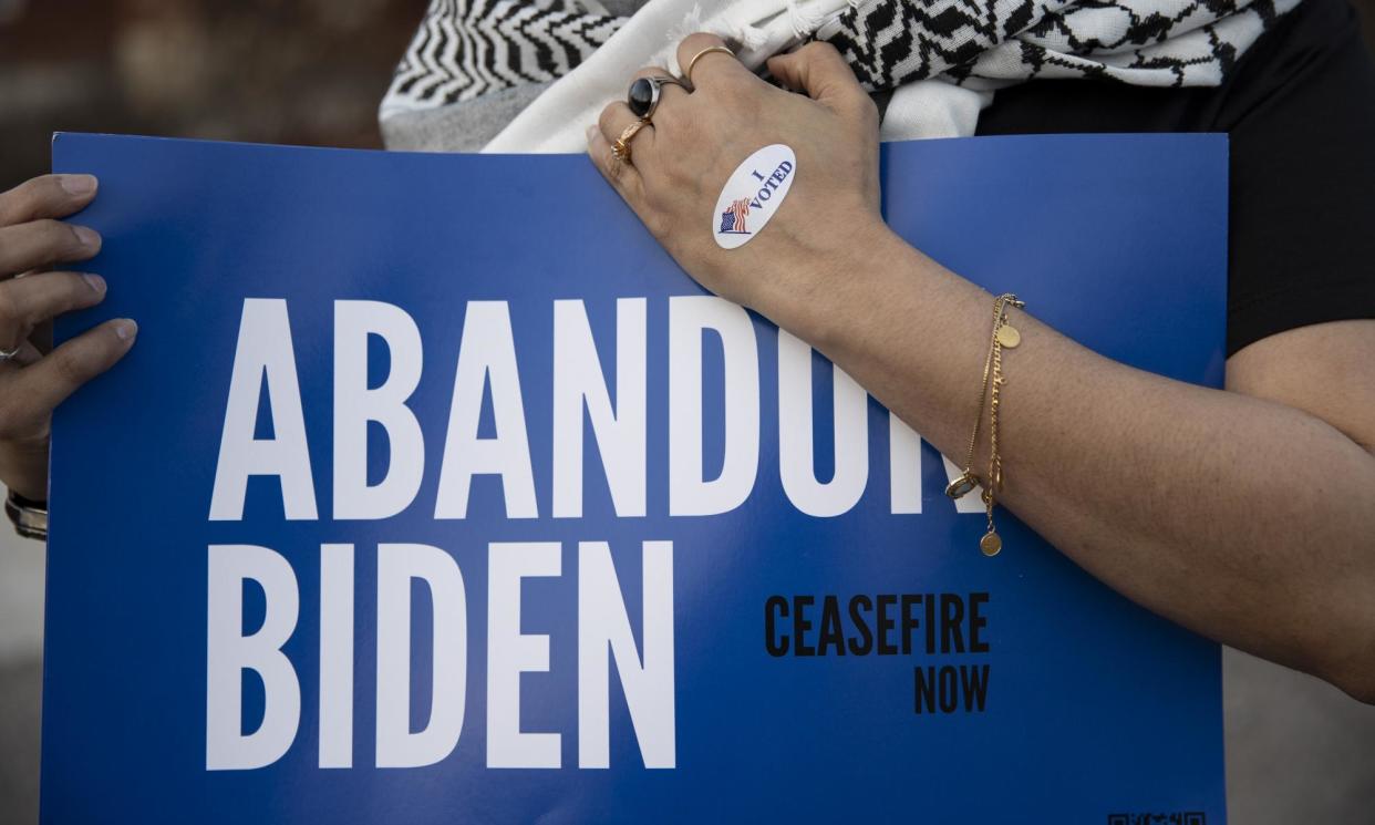 <span>Farah Khan holds a sign near a voting site to encourage voters to vote 'uncommitted' in Michigan primaries in Dearborn, Michigan, on 27 February 2024.</span><span>Photograph: Anadolu/Getty Images</span>