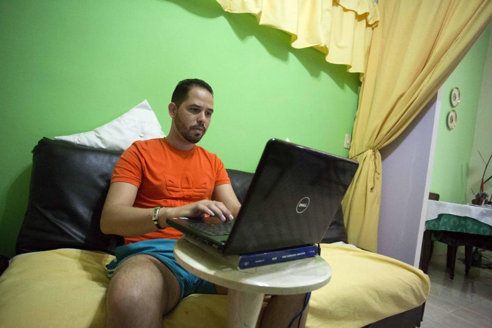In this Jan. 6, 2017 photo Roberto Carlos Villamar uses his laptop on the new experimental internet in the living room of his home in Havana, Cuba. For many Cubans, the start of home internet in December breaks a longstanding barrier against private internet access in a country whose communist government remains deeply wary about information technology undermining its near-total control of media, political life and most of the economy. (AP Photo/Desmond Boylan)
