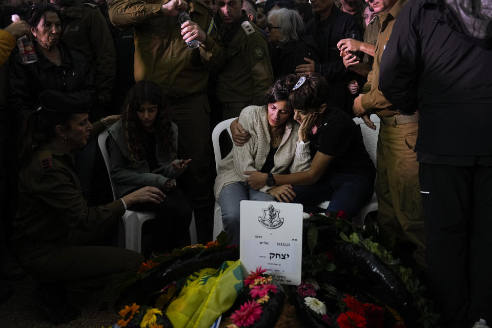 Family and friends of Israeli soldier Col. Itzhak Ben Basat mourn over his grave during his funeral in Kfar Tavor, Israel, Wednesday, Dec. 13, 2023. Ben Basat, 44, was killed during the Israeli military's ground operation in the Gaza Strip. while the army is battling Palestinian militants in the war ignited by Hamas' Oct. 7 attack into Israel. (AP Photo/Ariel Schalit)