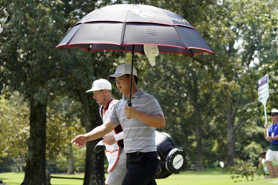 Tom Kim shields from the sun with an umbrella during the second round of the St. Jude Championship golf tournament Friday, Aug. 11, 2023, in Memphis, Tenn. (AP Photo/George Walker IV)
