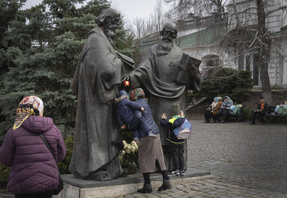 People pray at a sculpture of founding monks of the Monastery of the Caves, also known as Kyiv-Pechersk Lavra, one of the holiest sites of Eastern Orthodox Christians, in Kyiv, Ukraine, Friday, March 24, 2023. Tensions are on the rise at a prominent Orthodox monastery in Kyiv where the monks are facing eviction later this month. The Ukrainian government accuses the monks of links to Moscow, even though they claim to have severed ties with the Russian Orthodox Church following Russia's full-scale of invasion of Ukraine. (AP Photo/Efrem Lukatsky)