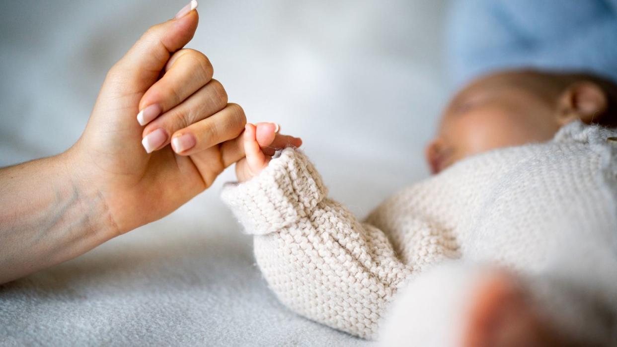 close up of mothers hand holding newborn babys hand
