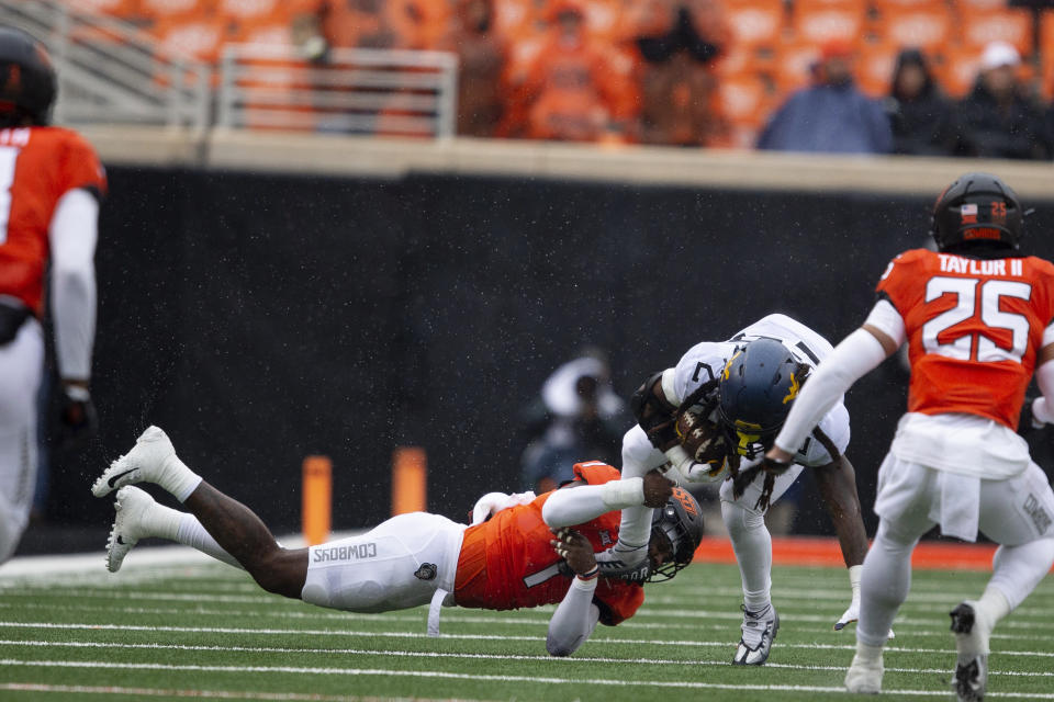 Oklahoma State linebacker Xavier Benson tackles West Virginia running back Tony Mathis Jr. (24) in the first half of the NCAA college football game in Stillwater, Okla., Saturday Nov. 26, 2022. (AP Photo/Mitch Alcala)