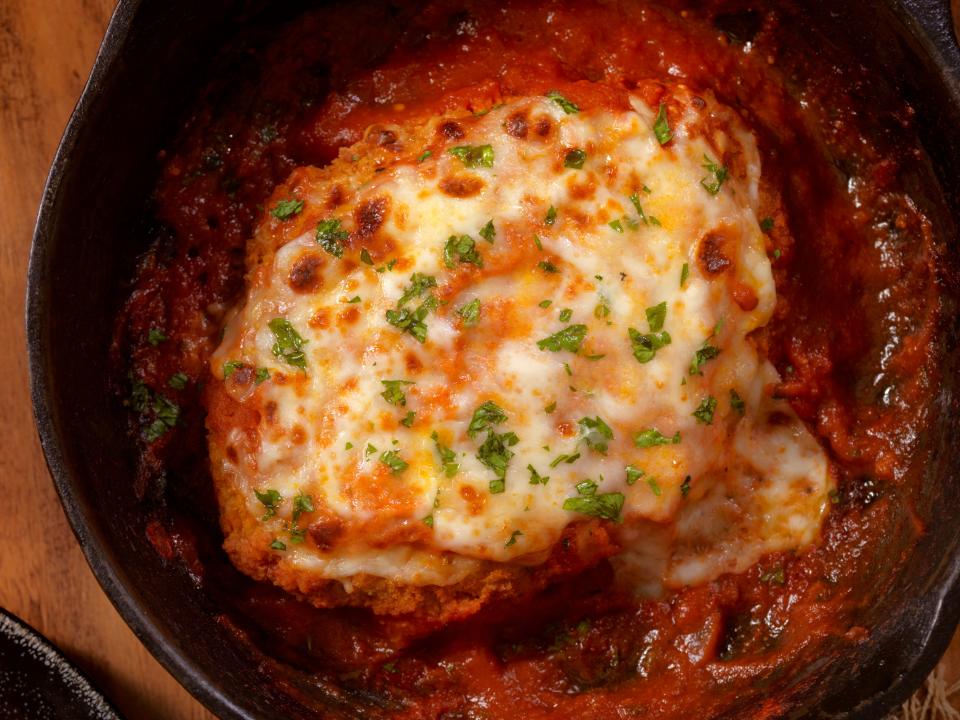 Chicken parmigiana in a black baking dish.