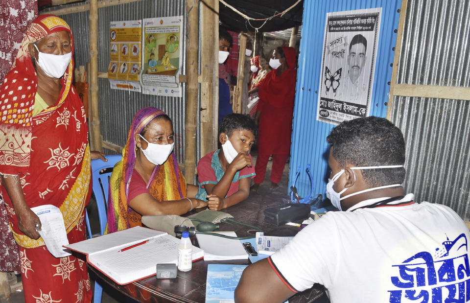 In this photo provided by Bidyanondo Foundation, a doctor writes a prescription for a patient after arriving at Banishanta village near Mongla seaport in southwestern region of Bangladesh, Sept. 1, 2020. A Bangladeshi charity has set up a floating hospital turning a small tourist boat into a healthcare facility to provide services to thousands of people affected by this year's devastating floods that marooned millions. (Bidyanondo Foundation via AP)