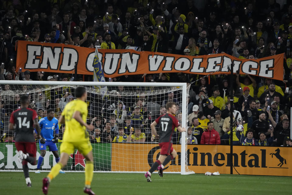 Fans hold up lights as a sign against gun violence is displayed during the first half of an MLS soccer match between Nashville SC and Toronto FC on Saturday, April 8, 2023, in Nashville, Tenn. The actions were in honor of the victims of a mass shooting at the Covenant School last month in Nashville. (AP Photo/Mark Humphrey)