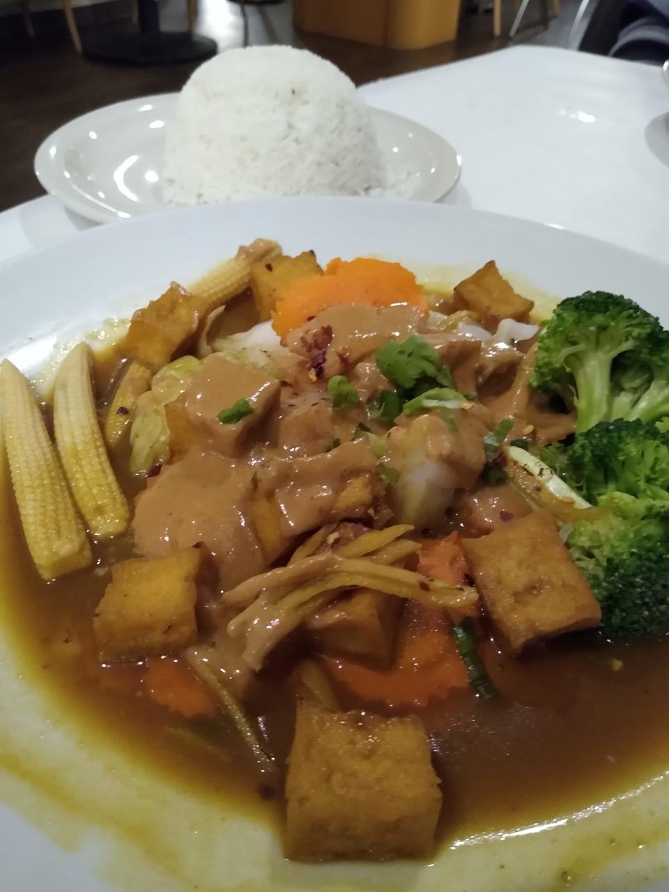 Tofu Rama at Cilantro is seasoned with ginger and curry powder on top of broccoli, carrots, baby corn and cabbage. It is served with Thai peanut sauce and white rice.