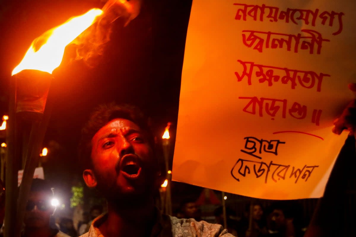 An activist displays a banner and shout slogans during a torch rally to protest against rising fuel prices in Dhaka (AFP via Getty)