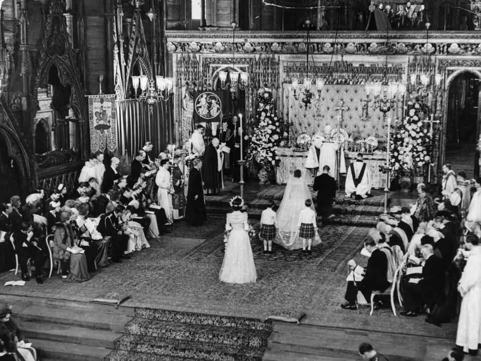 Queen Elizabeth II (then Princess Elizabeth) and Prince Philip kneel at the altar in Westminster Abbey as they get married.