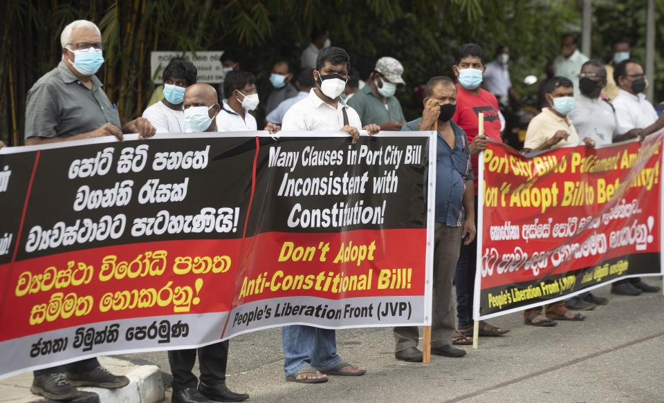 Nearly two dozen protestors belonging to the People's Liberation Front display banners against the Chinese built port city project in Colombo, Sri Lanka, Wednesday, May 19, 2021. Sri Lanka's top court has ruled that some provisions of legislation to set up a powerful economic commission in a Chinese-built port city violate the constitution and require approval by a public referendum to become law. (AP Photo/Eranga Jayawardena)