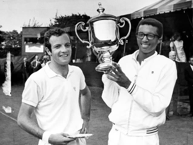<p>Walter Kelleher/NY Daily News Archive via Getty</p> Arthur Ashe holds trophy after defeating Tom Okker
