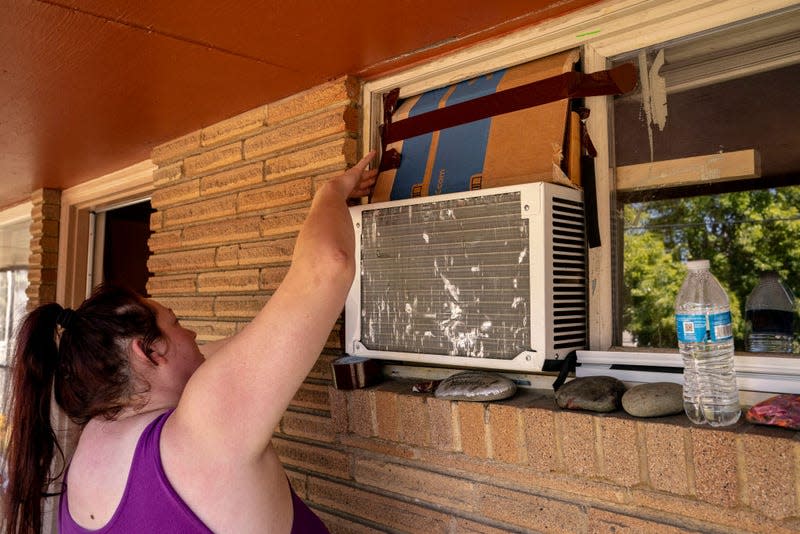 Kirstie Allemand arranges cardboard above an air conditioning unit in her window during soaring temperatures on July 28, 2022 in Ellensburg, Washington.