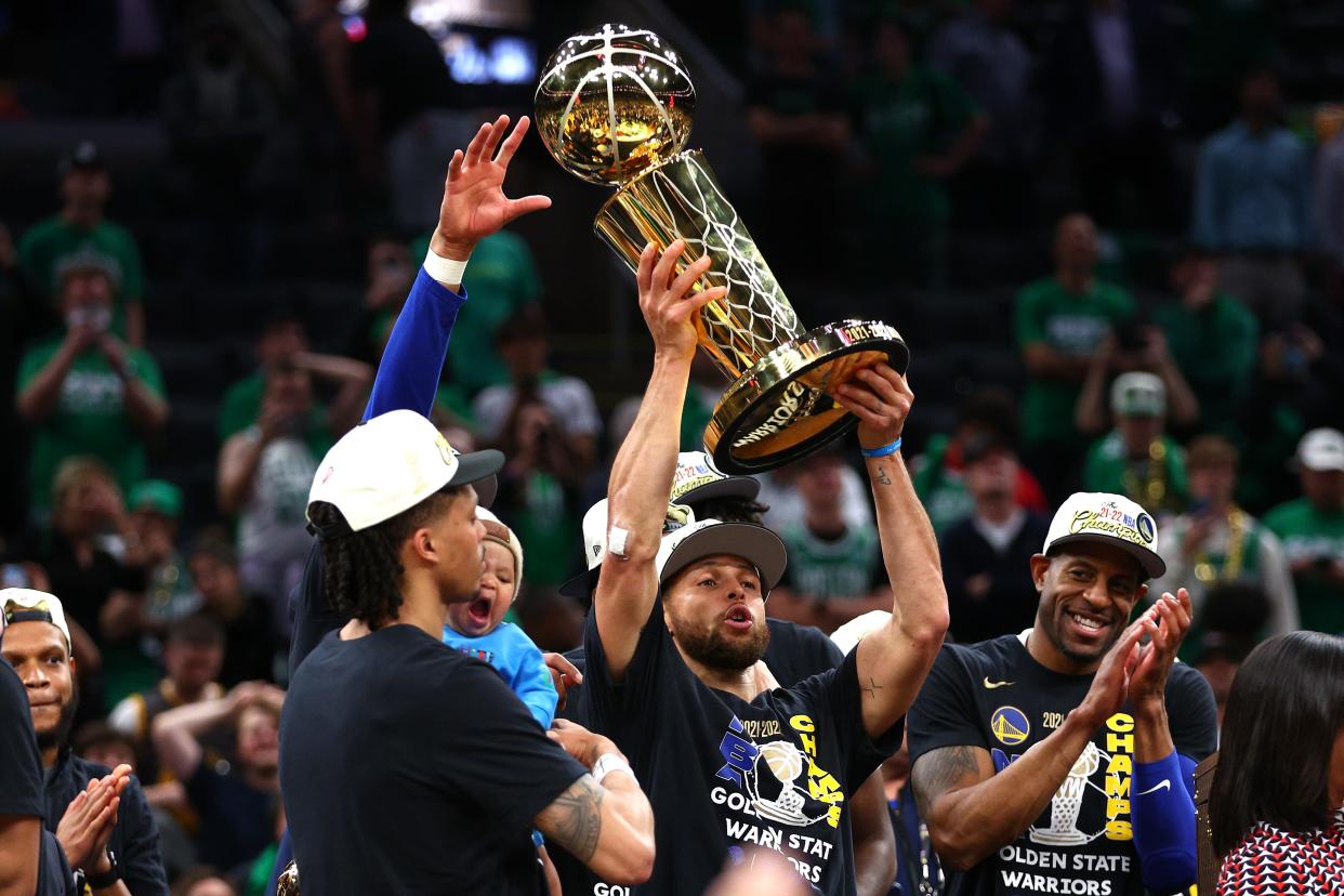 Steph Curry raises the Larry O'Brien Trophy.