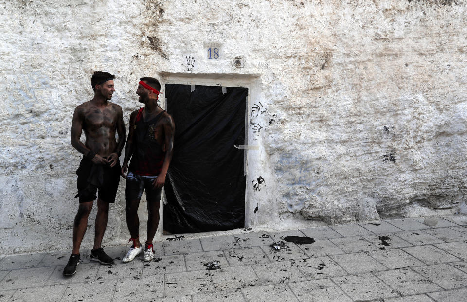 In this photo taken on Friday, Sept. 6, 2019, men painted with black grease celebrate during the traditional festivities of the Cascamorras festival in Baza, Spain. During the Cascamorras Festival, and according to an ancient tradition, participants throw black paint over each other for several hours every September 6 in the small town of Baza, in the southern province of Granada. The "Cascamorras" represents a thief who attempted to steal a religious image from a local church. People try to stop him, chasing him and throwing black paint as they run through the streets. (AP Photo/Manu Fernandez)