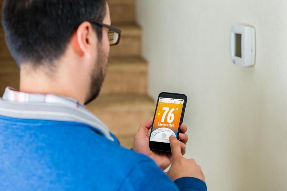 Man changing thermostat temperature on phone