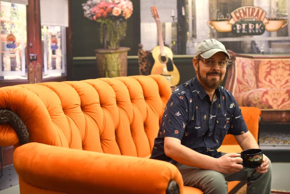 James Michael Tyler, aka Gunther from "Friends," sits on an orange couch in the pop-up's Central Perk coffee house.