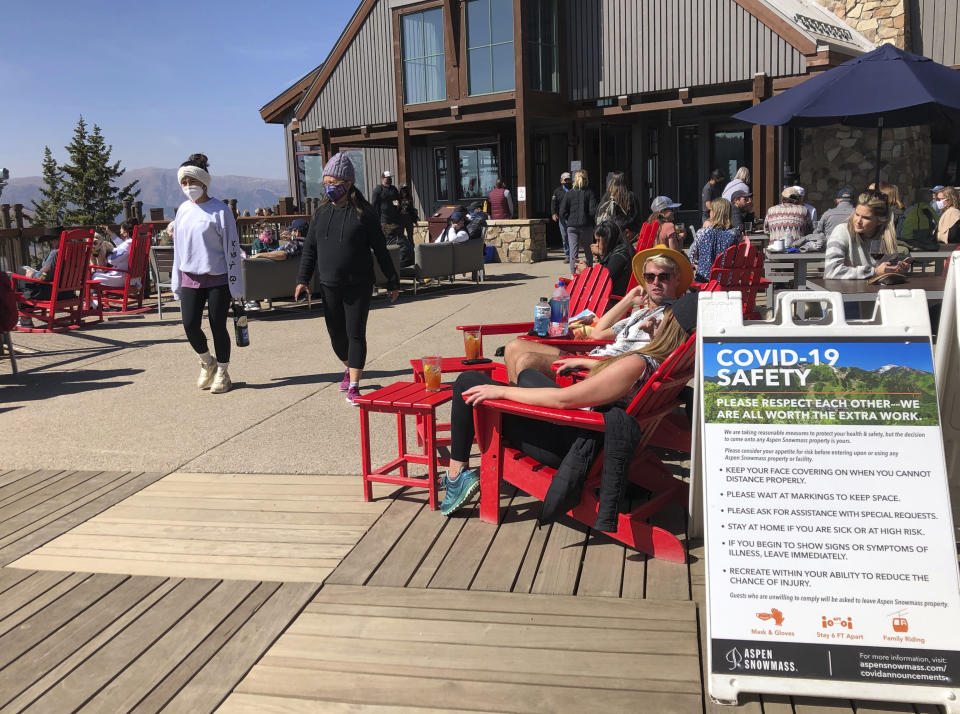 In this Oct. 3, 2020 photo, visitors to the top of Aspen Mountain eat and take in the sun in an expanded outdoor seating area in Aspen, Colo. Aspen has taken numerous precautions to prevent the spread of COVID-19 during the pandemic, including mask mandates and outdoor seating options. (AP Photo/John Marshall)