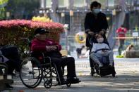 A woman pushes a stroller with a little girl, in a park in Shanghai