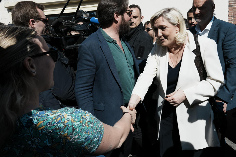 French far-right leader Marine Le Pen shakes hands with a resident as she campaigns in Saint-Remy-sur-Avre, western France, Saturday, April 16, 2022. Marine Le Pen is trying to unseat centrist President Emmanuel Macron, who has a slim lead in polls ahead of France's April 24 presidential runoff election. (AP Photo/Thibault Camus)