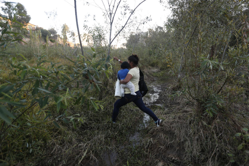 Yesenia Martinez, 24, carries her eight-month-old son Daniel as she looks for a place to cross the U.S. border wall to surrender to border patrol and request asylum, in Tijuana, Mexico, Friday, Dec. 7, 2018. Martinez surrendered to waiting border guards while her partner Joel Mendez stayed behind in Tijuana to work, saying he feared he'd be deported if he crossed. (AP Photo/Rebecca Blackwell)