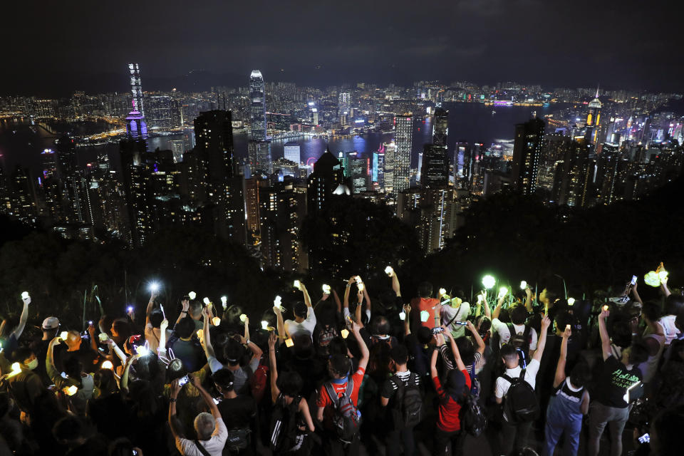 FILE - In this Friday, Sept. 13, 2019 file photo, demonstrators hold up the mobile phone lights as they form a human chain at the Peak, a tourist spot in Hong Kong. Hong Kong has a long tradition of public demonstrations dating from its days as a British colony. However, protest activity has been tamped down since Beijing enacted a sweeping security law in June 2020, banning speech seen as promoting secession. (AP Photo/Kin Cheung)