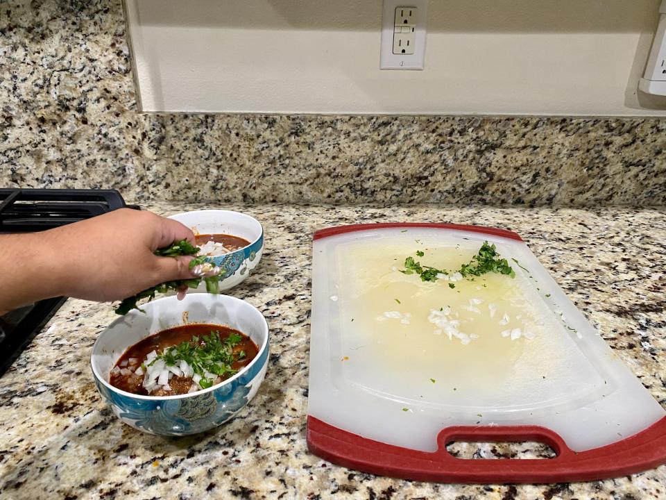 Sprinkling cilantro into a bowl of birria.