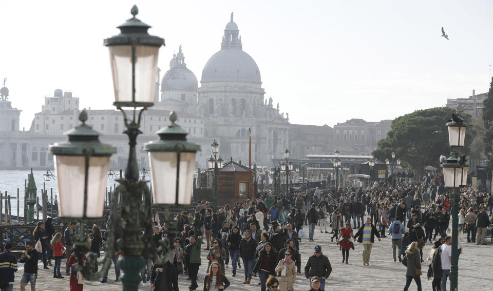 FILE - Tourists stroll in downtown Venice, Italy, Nov. 12, 2016. Starting in January, Venice will oblige day-trippers to make reservations and pay a fee to visit the historic lagoon city. On many days, the heart of Venice is overwhelmed by visitors, who often far outnumber residents. Venice officials on Friday unveiled new rules for day-trippers, which go into effect on Jan. 16, 2023. (AP Photo/Luca Bruno, File)