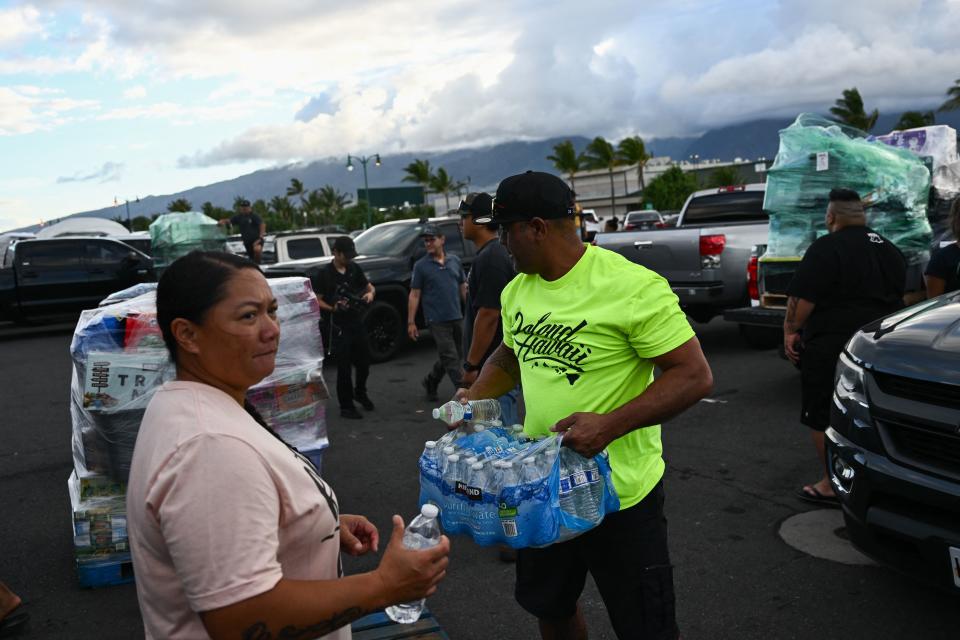 Volunteers load pallets of supplies and aid donations flown in from the Hawaiian island of Kauai into pickup trucks at the Kahului airport cargo terminal in the aftermath of the Maui wildfires.