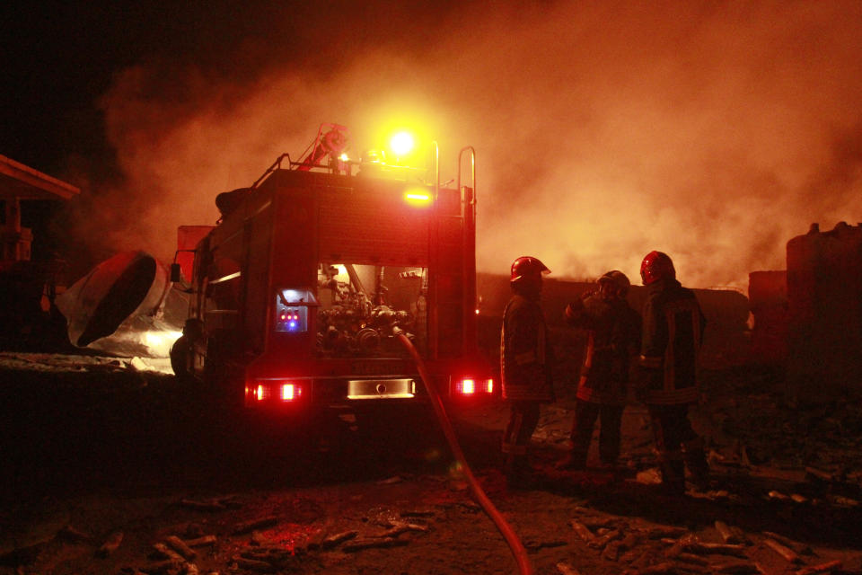 Iranian firefighters work on a burning tanker carrying fuel at the Islam Qala border with Iran, in Herat Province, west of Kabul, Afghanistan, Saturday, Feb. 13, 2021. A fuel tanker exploded Saturday at the Islam Qala crossing in Afghanistan's western Herat province on the Iranian border, injuring multiple people and causing the massive fire that consumed more than 500 trucks carrying natural gas and fuel, according to Afghan officials and Iranian state media. (AP Photo/Hamed Sarfarazi)