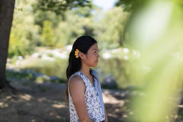 Ruzzelle Gasmen shows off an ear cuff attached to her hearing aid that was inspired by the star on the flag of the Philippines. (Gian-Paolo Mendoza/CBC - image credit)