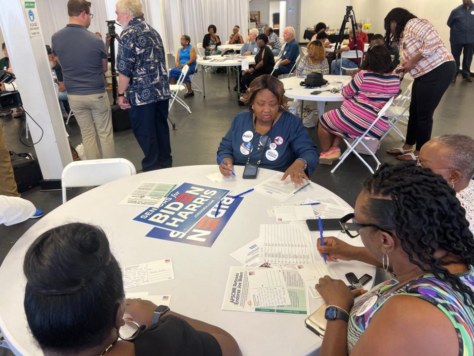 Evelyn Goldwire, with back to camera, along with Deborah Porter, Linda Barnes and Marva Davis write postcards to urge people to request a mail-in ballot and vote for Joe Biden, in Quincy, Monday, June 17, 2024.