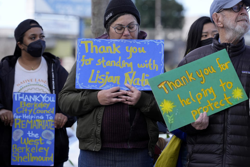 People hold up signs while listening to speakers at a news conference in Berkeley, Calif., Wednesday, March 13, 2024. Berkeley's City Council voted unanimously Tuesday, March 12, 2024, to adopt an ordinance giving the title of the land to the Sogorea Te' Land Trust, a women-led, San Francisco Bay Area collective that works to return land to Indigenous people and that raised the funds needed to reach the agreement. (AP Photo/Jeff Chiu)