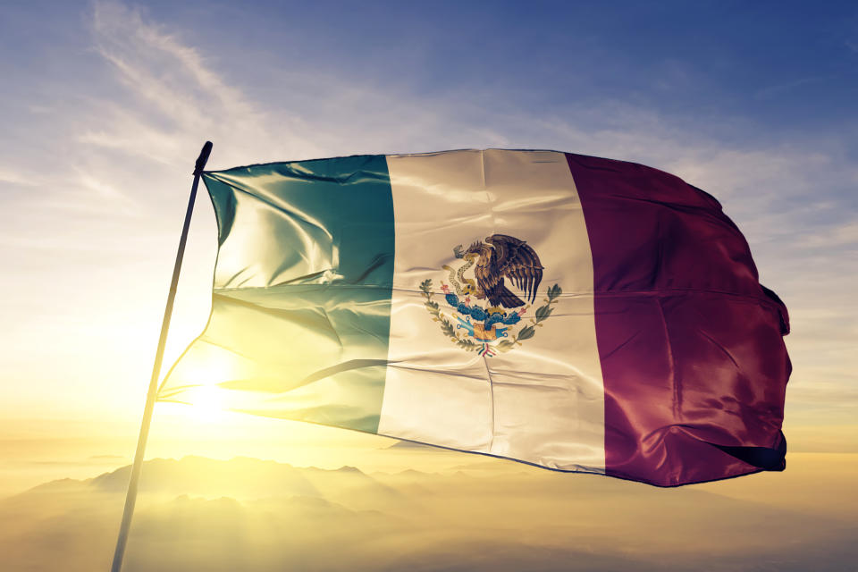 Mexico Mexican flag on flagpole textile cloth fabric waving on the top sunrise mist fog