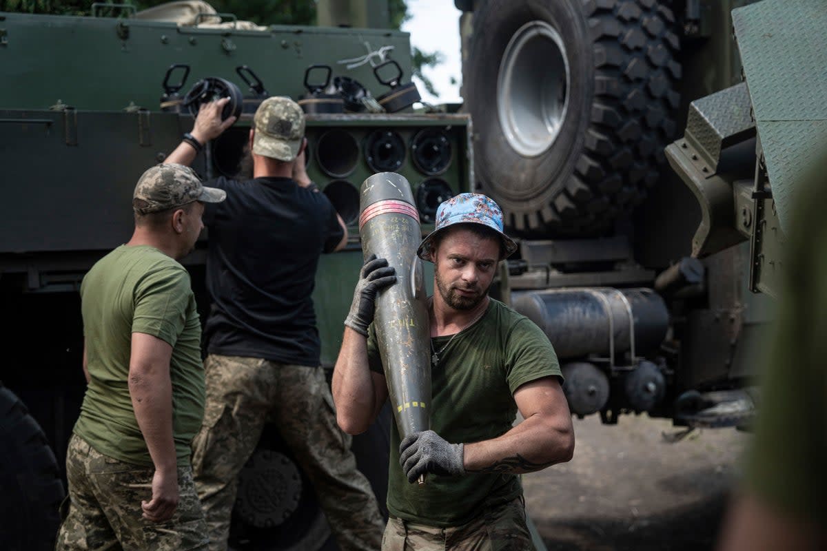 A Ukrainian serviceman carries a 155mm shell into self-propelled howitzer 