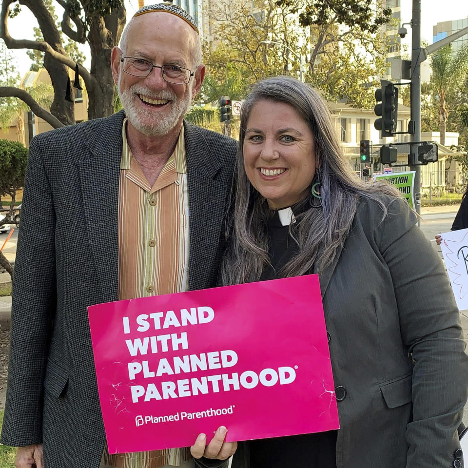 In this photo provided by Felicity Figueroa, Rabbi Stephen Einstein, left, founding rabbi of Congregation B’nai Tzedek in Fountain Valley, Calif., stands with the Rev. Sarah Halverson-Cano, senior pastor of Irvine United Congregational Church in Irvine, Calif., at a rally supporting abortion access, in Santa Ana, Calif., May 3, 2022. (Felicity Figueroa via AP)