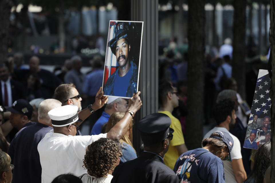 FILE - In this Sept. 11, 2019, file photo, a photograph of fallen firefighter Leon Smith, Jr. is held up during a ceremony marking the 18th anniversary of the attacks of Sept. 11, 2001 at the National September 11 Memorial, in New York. The coronavirus pandemic has reshaped how the U.S. is observing the anniversary of 9/11. The terror attacks' 19th anniversary will be marked Friday, Sept. 11, 2020, by dueling ceremonies at the Sept. 11 memorial plaza and a corner nearby in New York. (AP Photo/Mark Lennihan, File)