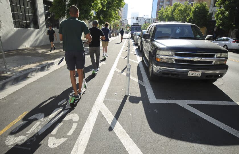 People riding electric scooters use a bike lane next to where cars park away from the curb on J Street, near the Eleventh Avenue intersection in downtown on Tuesday, July 9, 2019 in San Diego, California.