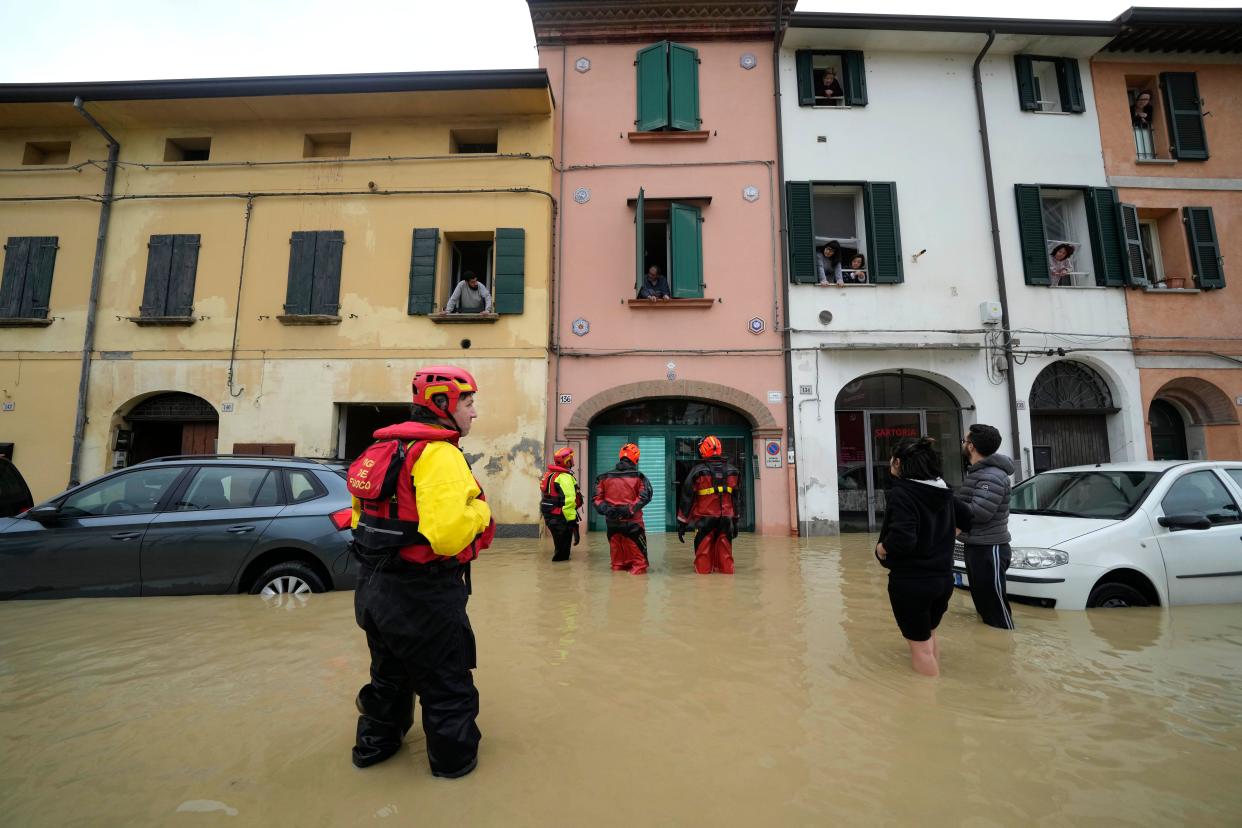 Firefighters talk with residents of the flooded village of Castel Bolognese. (Reuters)