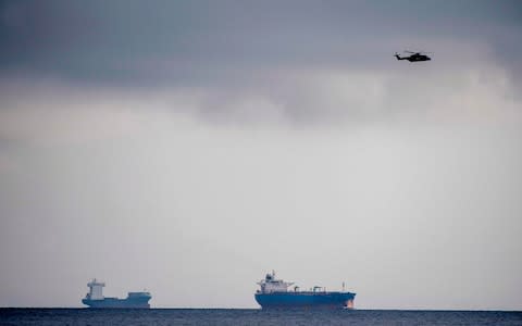 A helicopter flies over the sea off of Copenhagen Harbour where the world's largest privately-built submarine sank - Credit: Bax Lindhart/AFP